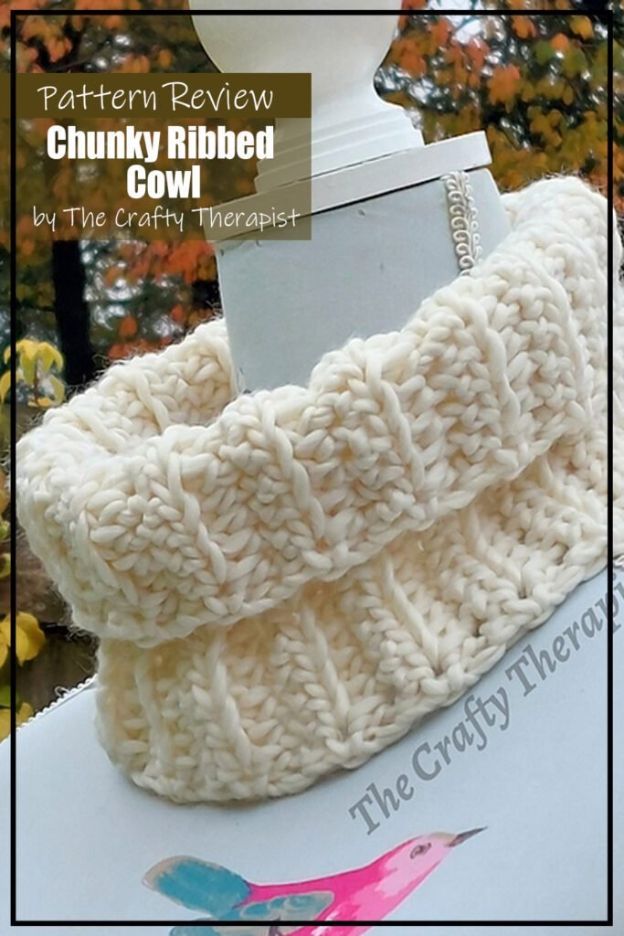 Chunky Ribbed Cowl crochet pattern sample is made with a super bulky cream coloured yarn. The crochet project is modeled on a dress form. It is outside and there are golden fall leaves in the background. The text on the image reads "Chunky RIbbed Cowl by The Craft Therapist Pattern Review".