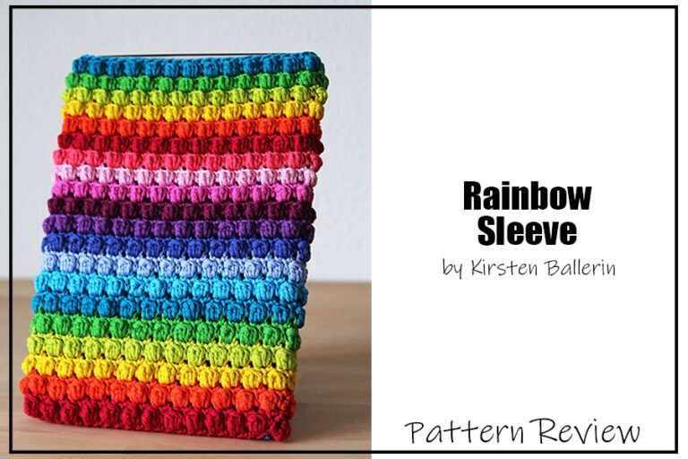 Rainbow Sleeve by Kirsten Ballering crochet pattern sample is knit using a rainbow of yarn colours from red at the bottom up to blue at the top (the rainbow repeats twice). The texture of the Rainbow Sleeve is a series of bumpy bobble stitches. The text on this images reads "Rainbow Sleeve by Kirsten Ballering Pattern Review"