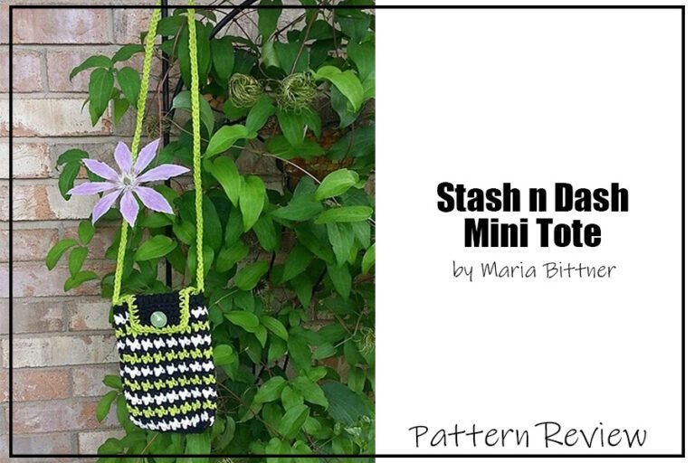 Stash 'n Dash Mini Tote by Maria Bittner crochet pattern sample is made using white, dark green, and light green yarn. Tote is hanging in front of a brick wall with green plants. The words on the image read "Stash 'n Dash Mini Tote by Maria Bittner Pattern Review".