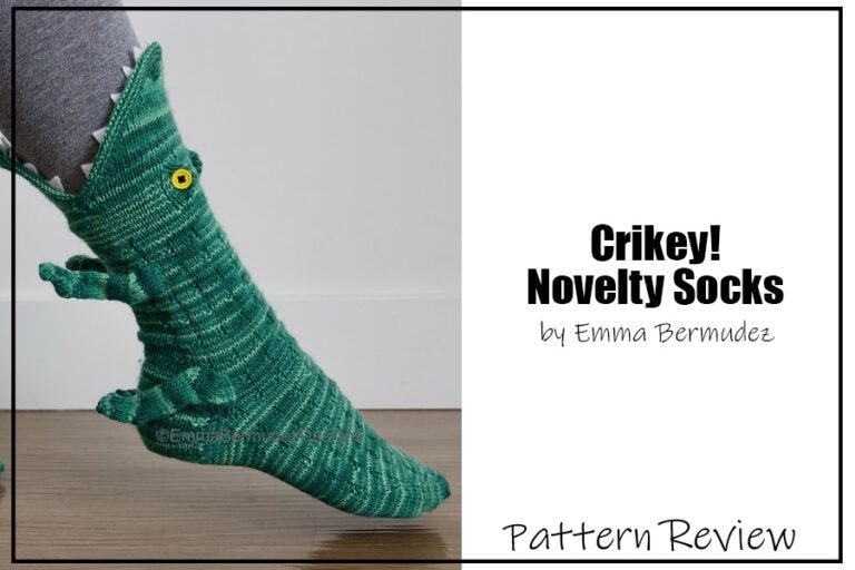 The Crikey! novelty sock knitting pattern sample is knit using a tonal variegated green yarn. The slipper socks look like a crocodile eating your foot - with the mouth opening at the top of the sock up on the calf of the model wearing this pattern. The Text on the image reads "Criky! Novelty Socks by Emma Bermudez Pattern Review".