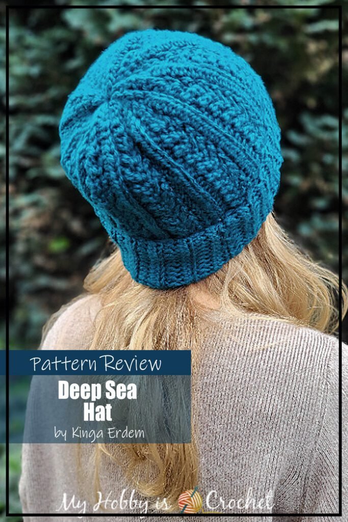 The Deep Sea Hat crochet pattern sample is made using a teal aran weight yarn and a 4 row repeat that makes a great texture on the hat. There is a foldover brim. The hat is modeled on a woman with blond hair and shows the back/crown of the hat. The text on the image reads "Deep Sea Hat by Kinga Erdem Pattern Review".
