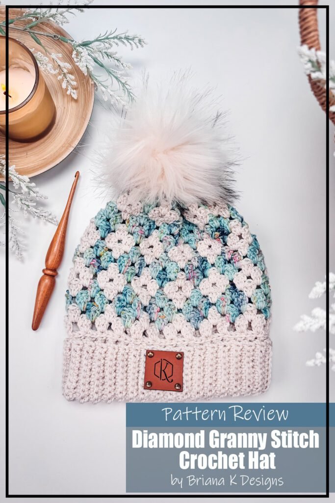 Diamond Granny Stitch Crochet Hat pattern sample is made using a white and light blue yarn. The two colours in the granny square pattern make a diamond shaped pattern on the hat. The ribbing of the hat is white. There is a white pompom. The text on the image reads "Diamond Granny Stitch Crochet Hat by Briana K Designs Pattern Review".