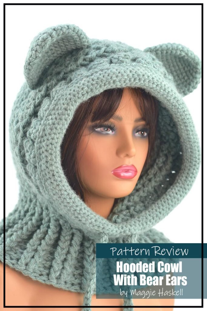 Hooded Cowl With Bear Ears crochet pattern sample is maded with a mint green yarn. The pattern is a mixture of hood and cowl. The crochet project is displayed on a plastic female mannequin head with a white background. The text on the image reads "Hooded Cowl With Bear Ears by Maggie Haskell Pattern Review".