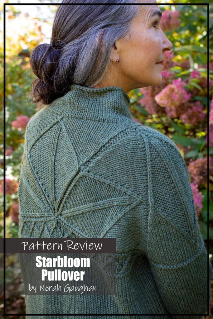 Starbloom knitting pattern sample is a beautiful green sweater pullover featuring a star motif made using twisted stitches and decreases. This picture shows the back of the sweater. The sweater is modeled on a woman wearing jeans standing outside in front of a flowering bush. The text on the image reads "Starbloom Pullover by Norah Gaughan Pattern Review".