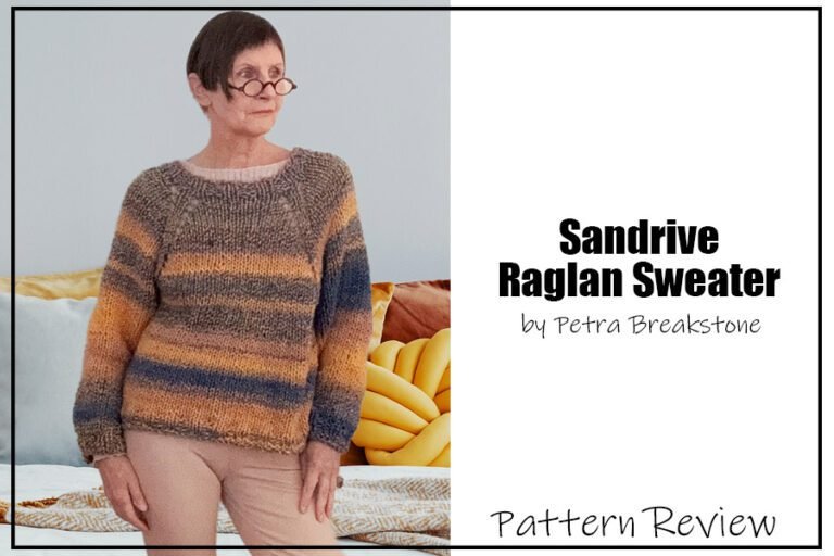 Sandrine Raglan Sweater sample is knit using aran weight yarn in yellows and blues. It is modeled on a woman with short brown hair standing wearing beige pants. The text on the image reads "Sandrine Raglan Sweater by Petra Breakstone Pattern Review."